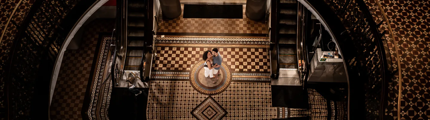 Couple embracing on a tiled floor between escalators